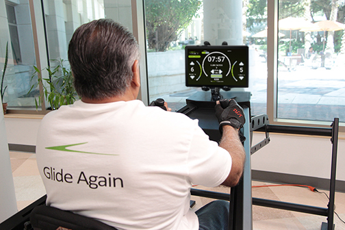 A man is using a Vitaglide exercise system while tracking his personal performance on a mounted tabllet.