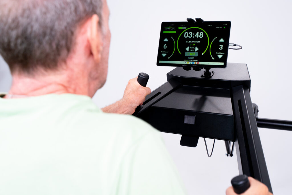 A man using a Vitaglide exercise system while tracking his personal performance.