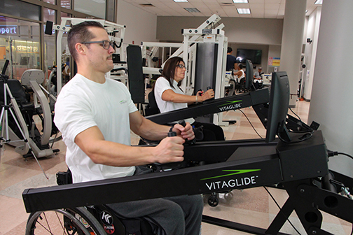A wheelchair-using man is working our on the Vitaflide in a gym.