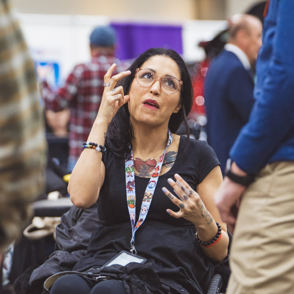 A woman is communicating in American Sign Language at Abilities Expo.