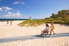 View of beach, with someone rolling up to the seaside via an accessible path.