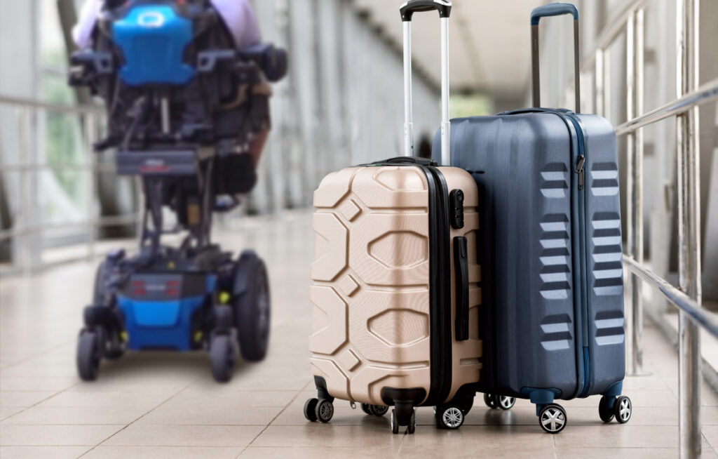 An elevated wheelchair featured with two rolling hardshell suitcases at the airport.