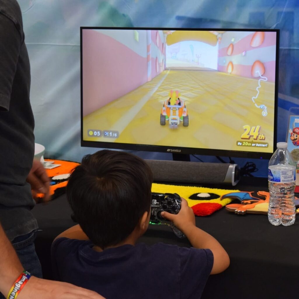 A young boy plays a racing game in front of a large video monitor.