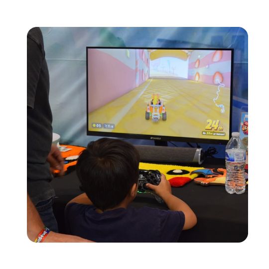 A young boy plays a racing game in front of a large video monitor.