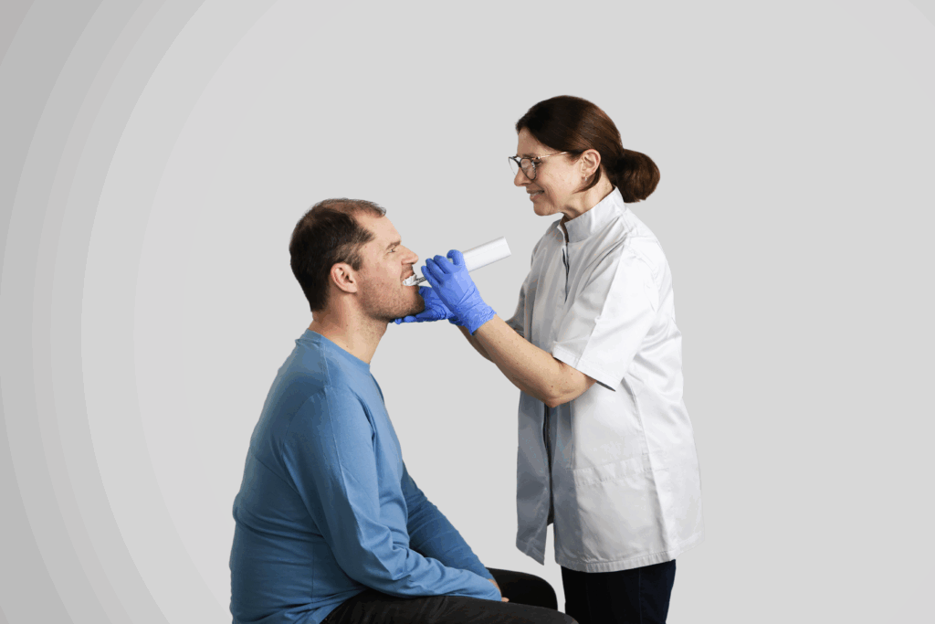 A dentist using the Samba robotic toothbrush from Curaprox to clean the teeth of a man in a blue shirt.