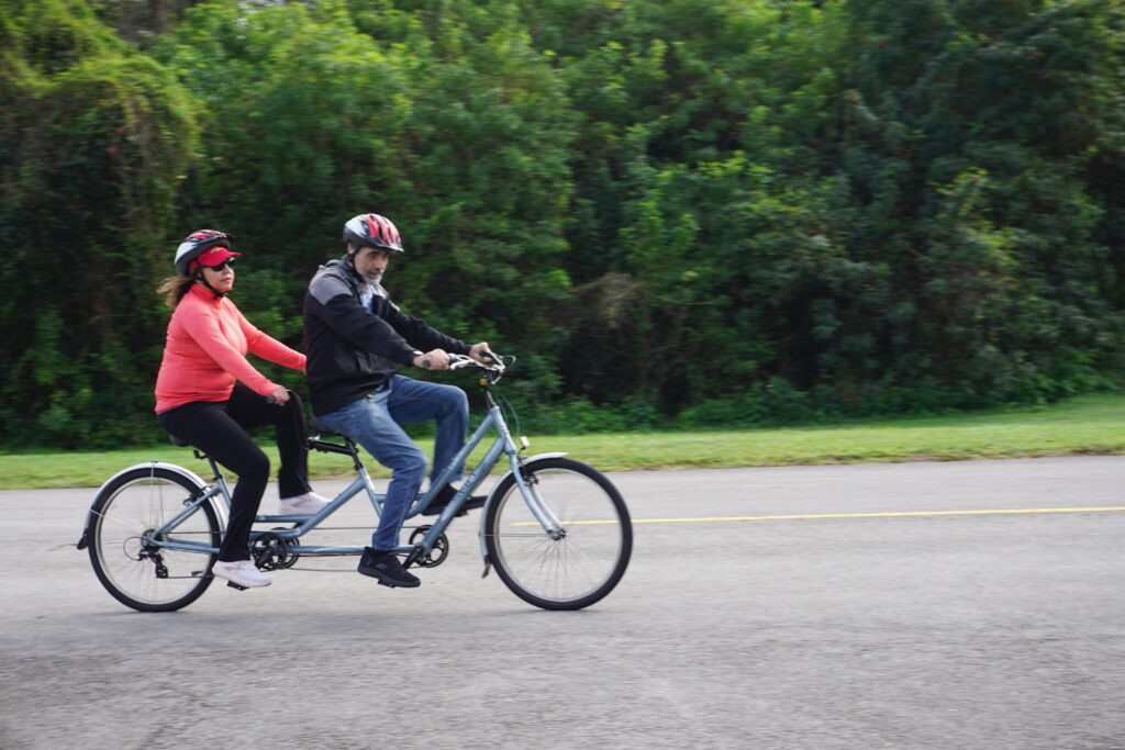 Two people are riding tandem bike in a park in Greater Fort Lauderdale.