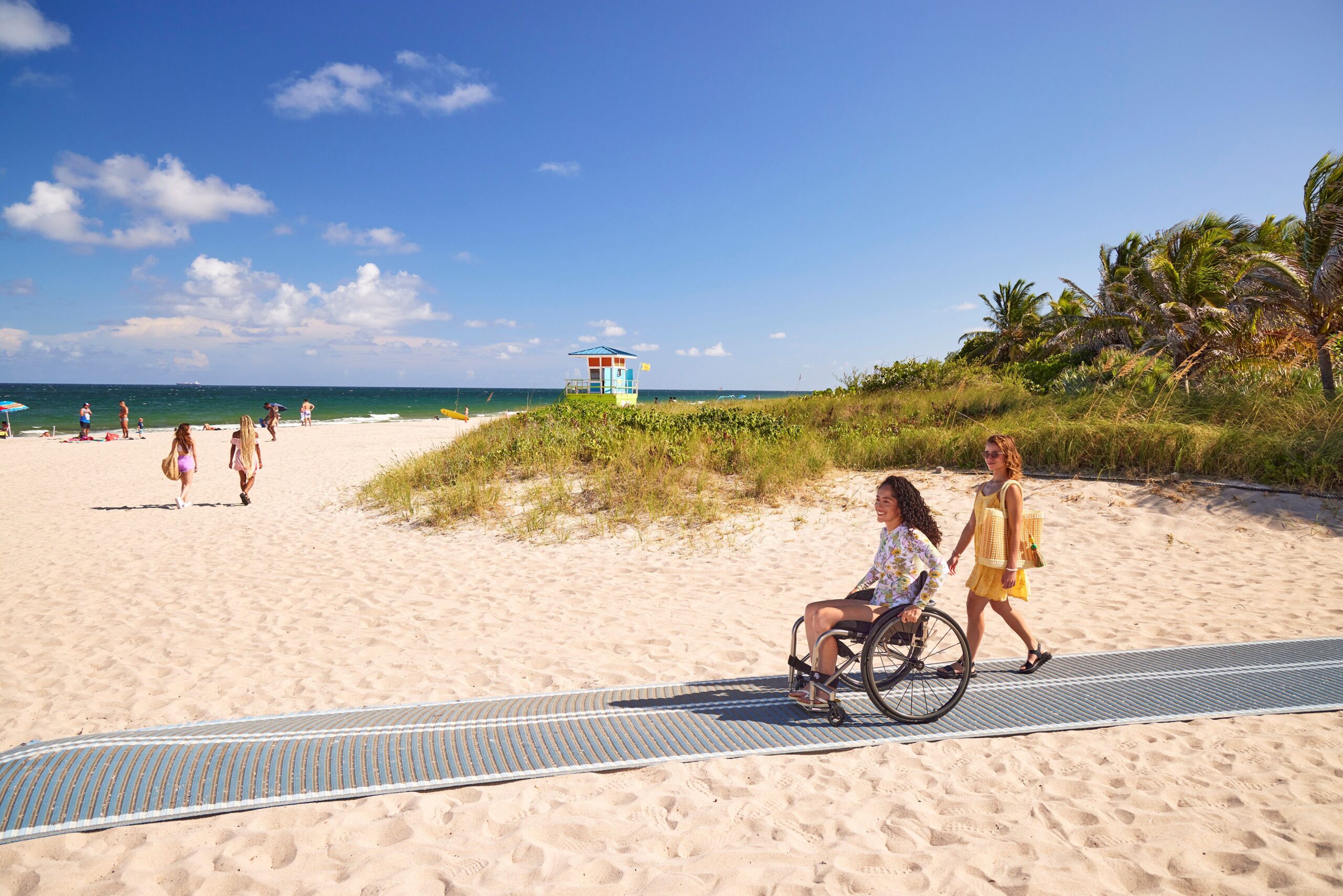 View of beach, with someone rolling up to the seaside via an accessible path.