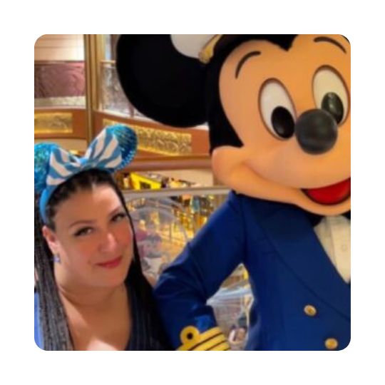 Accessible travel agent Yolanda is dressed up as Alice in Wonderland with Mickey Mouse.