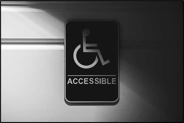 Black and white image of a sign on a door that has 'Accesible' on it