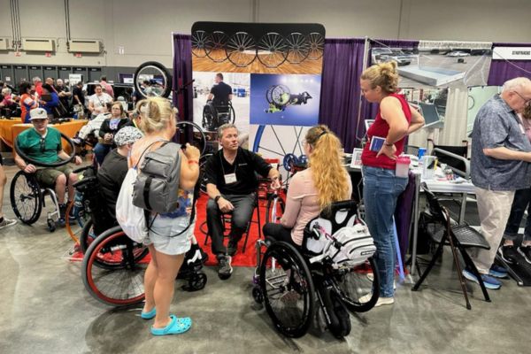 A group of people talk to a vendor at Abilities Expo.