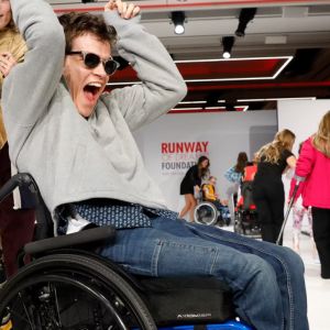 Several people decorate a runway, with a cheering man in the forefront