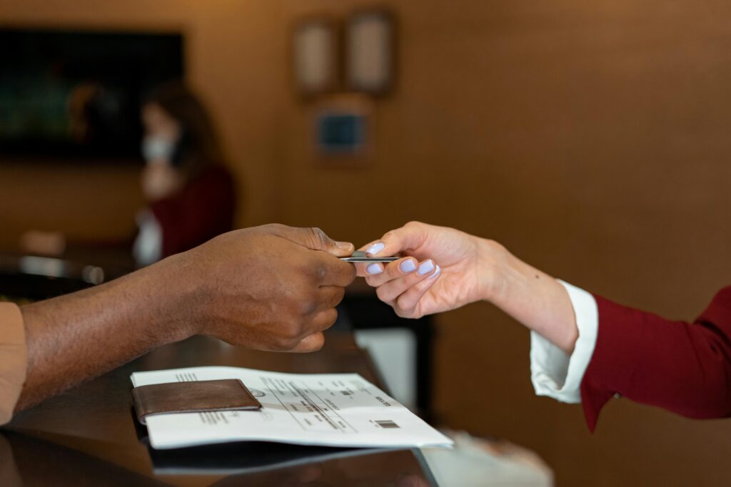 Picture of a woman's hand handing her credit card to someone at a counter