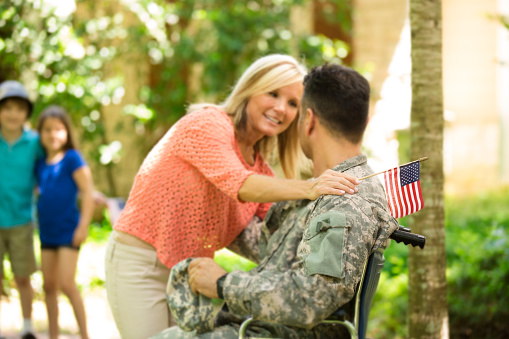 A disabled veteran is shown hugging his wife