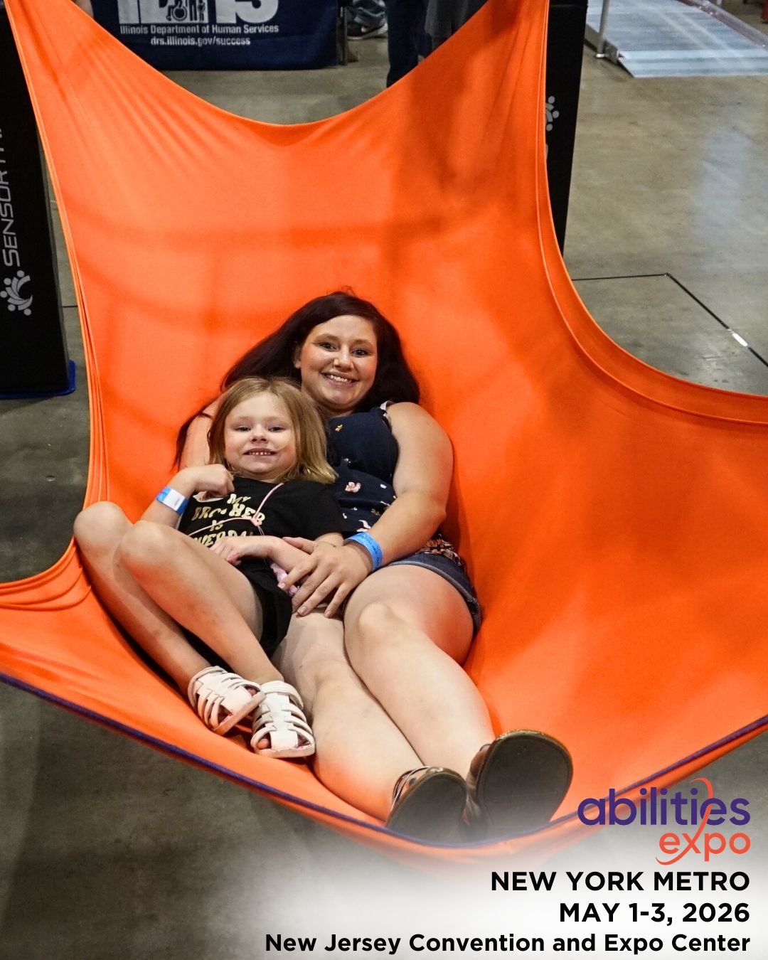 A woman and a little girl lounge together on a sling.