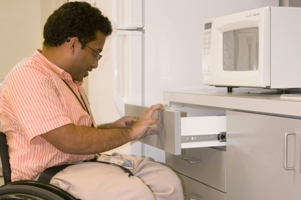 Man who is using a wheelchair navigates his kitchen