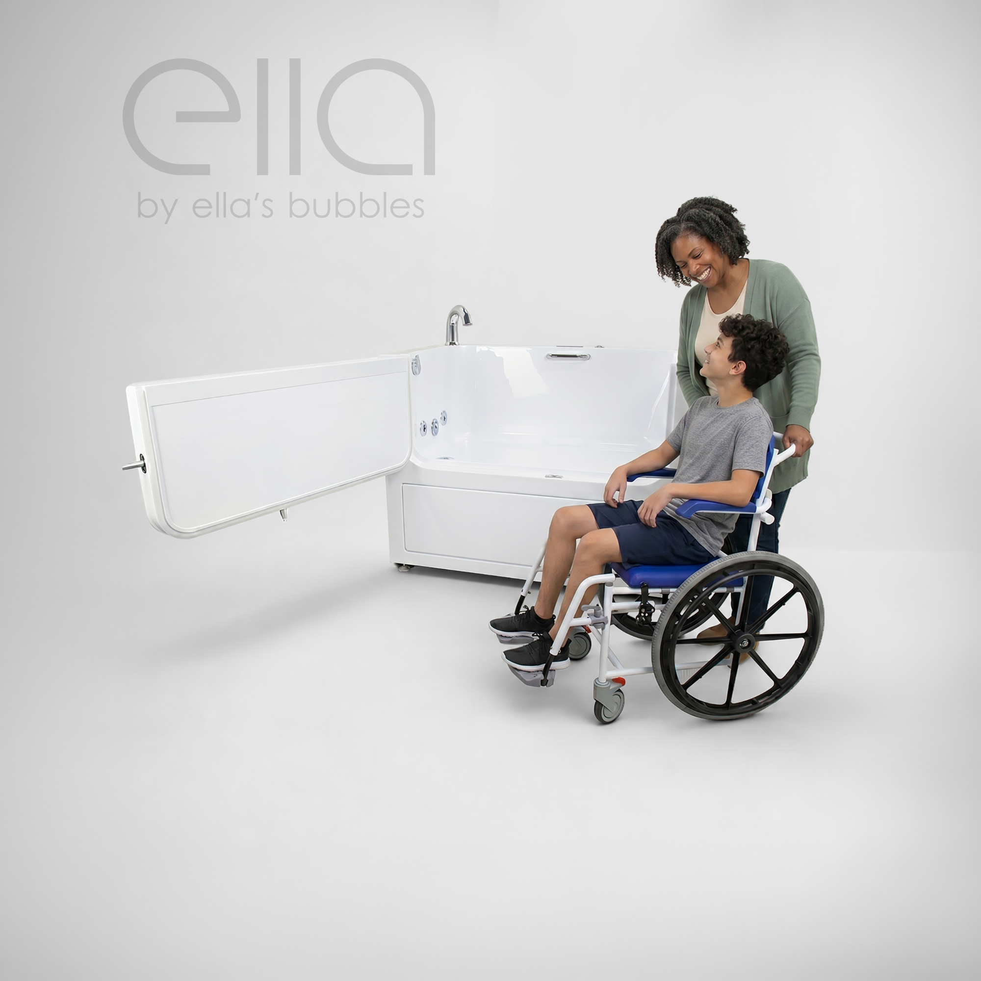 Woman assisting a smiling child seated in a wheelchair beside an Ella walk-in bathtub with an outward-opening door, highlighting accessible bathing and caregiver support.