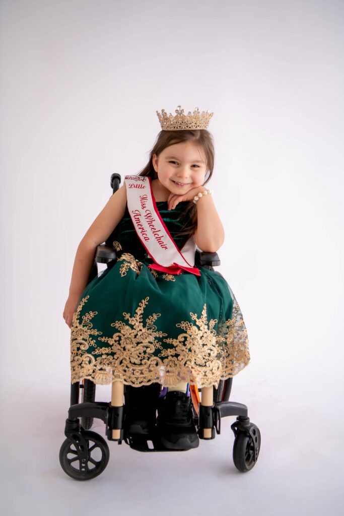 Little Miss Wheelchair America, Dahlia Swanson, posing in a dress, crown, and Little Miss Wheelchair sash.