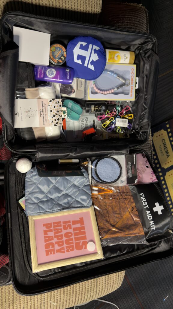 A Tramora Chick-in Medium Check-In Bag, combination lock, smooth wheels, ABS Hooks, Polycarbonate Hard-Shell. Filled with goodies
