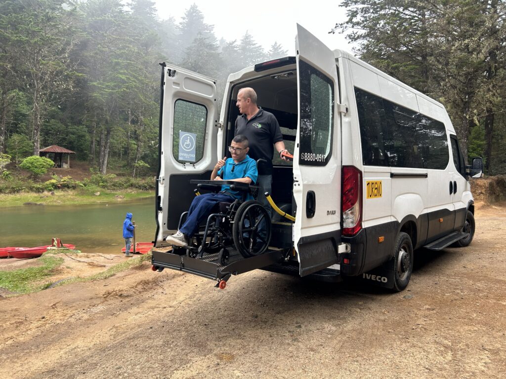 A man in a wheelchair being lowered down from an accessible van on a wheelchair lift while on an accessible vacation in costa rica
