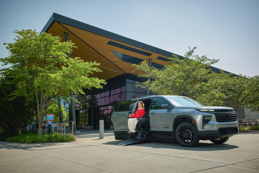 A woman exits the Next Gen Traverse in front of a large building