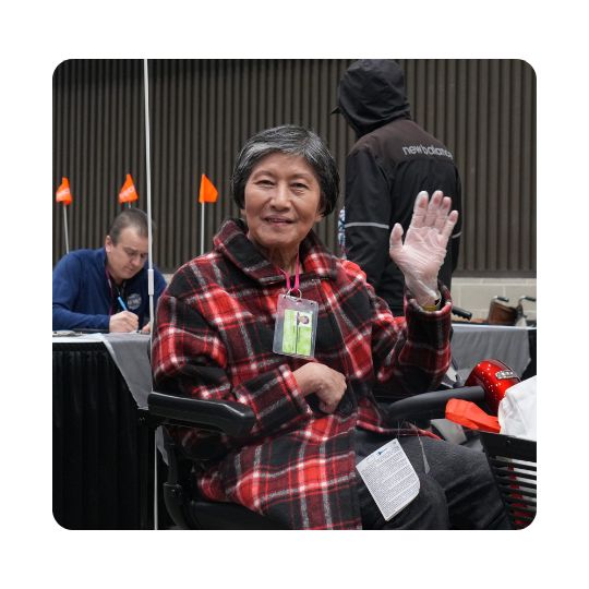An elderly woman is using a pride mobility loaner scooter at abilities expo