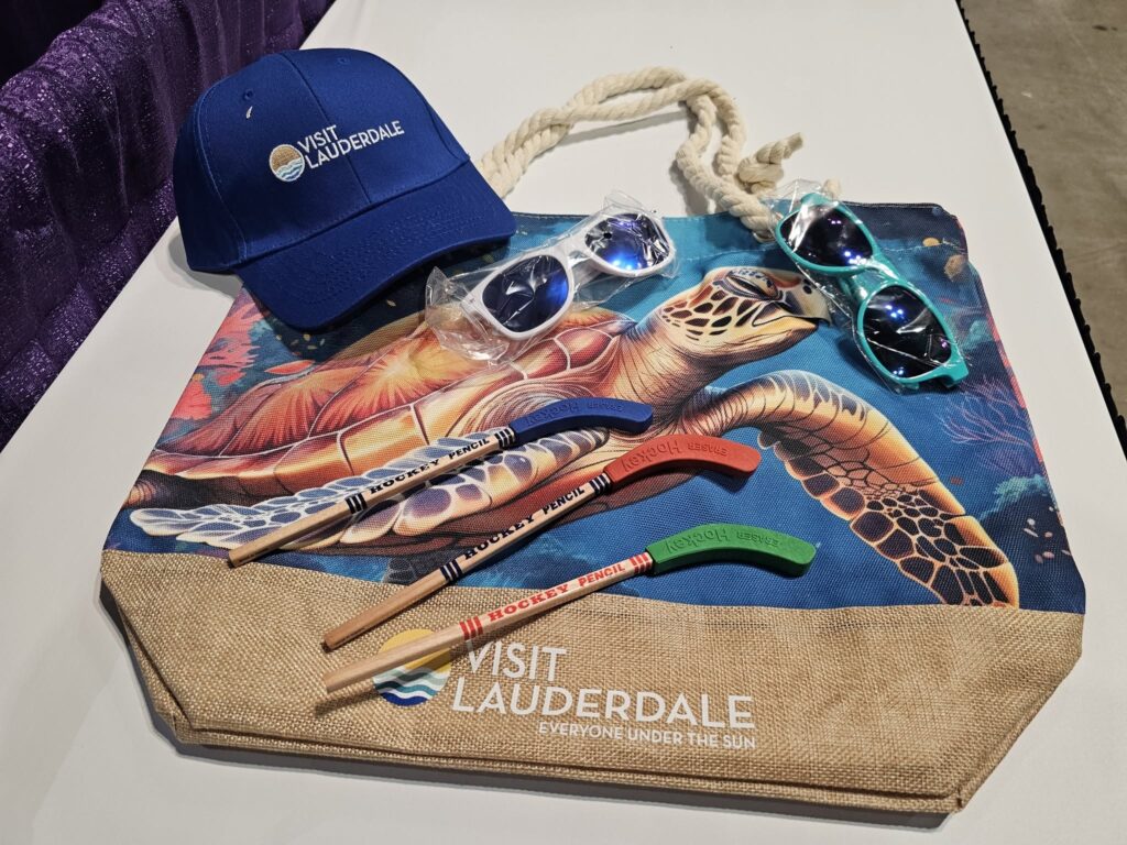 a beach bag filled with Visit Lauderdale swag. Sunglasses, a baseball cap, and pencils shaped like hockey sticks