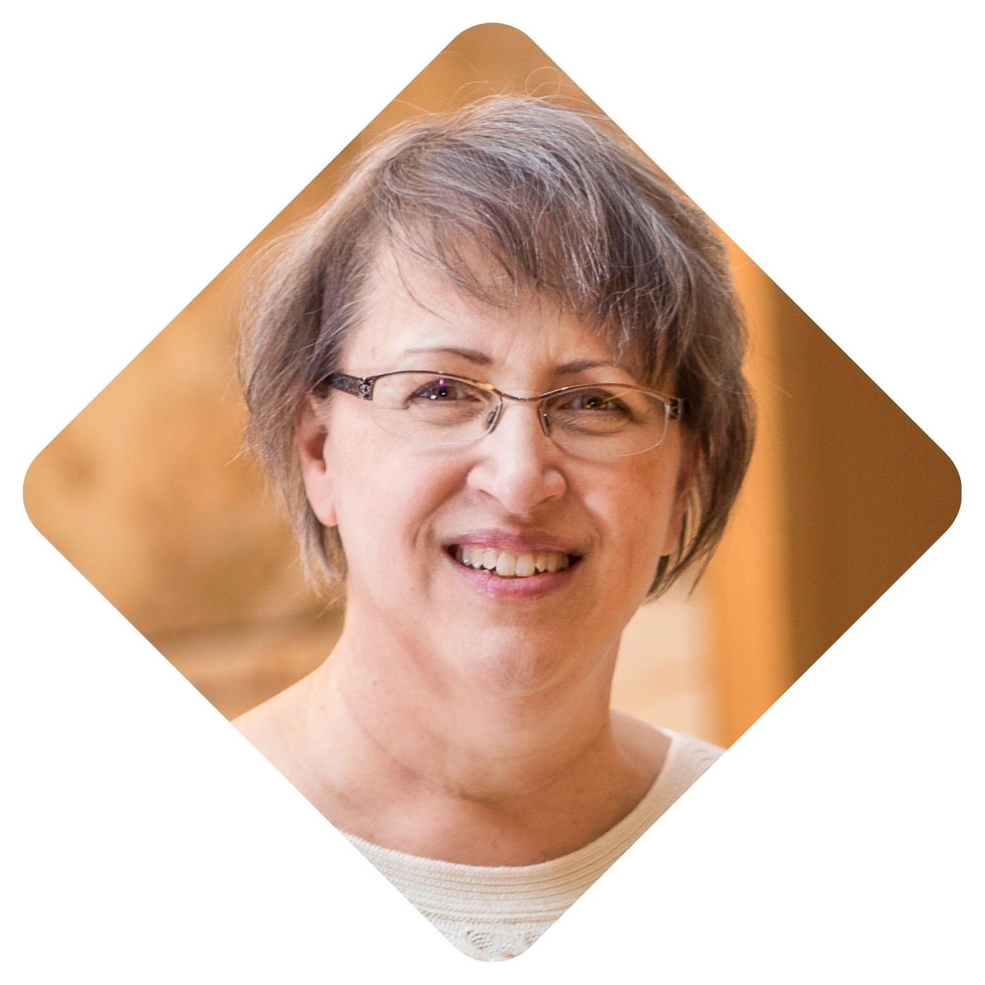 Headshot of Cindy Kolbe, smiling at camera wearing glasses and a white blouse.