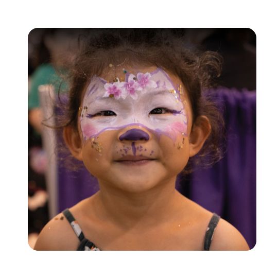 Close up shot of a little girl with pink and purple face paint