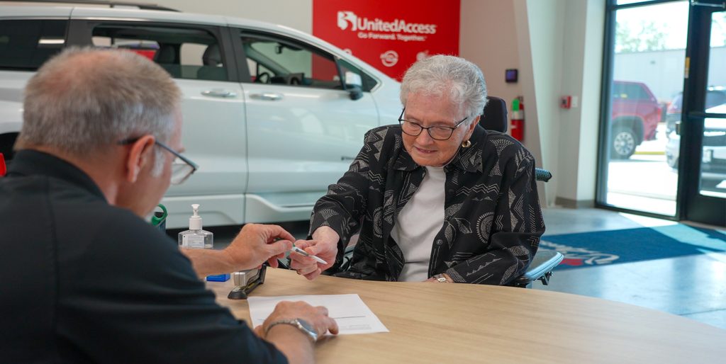 Woman signs paperwork to get her car checked for her wheelchair accessible vehicle