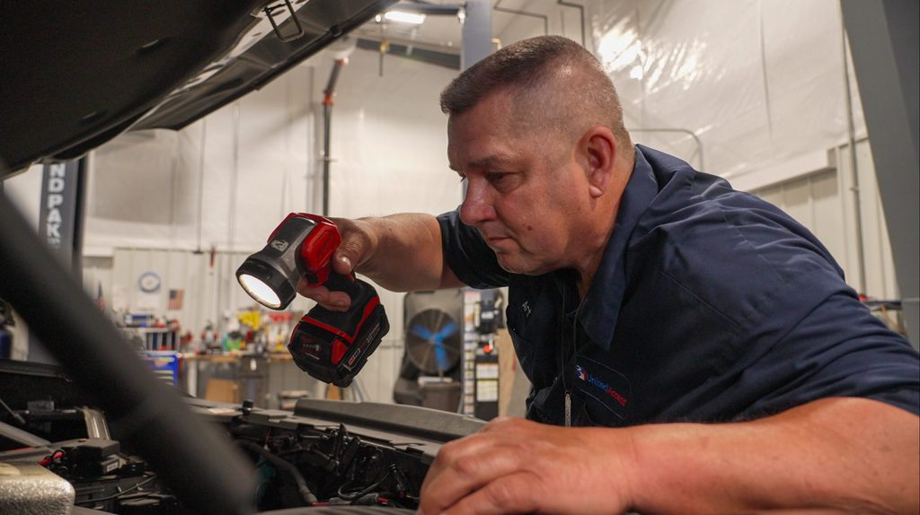 Man services a car by checking under the hood